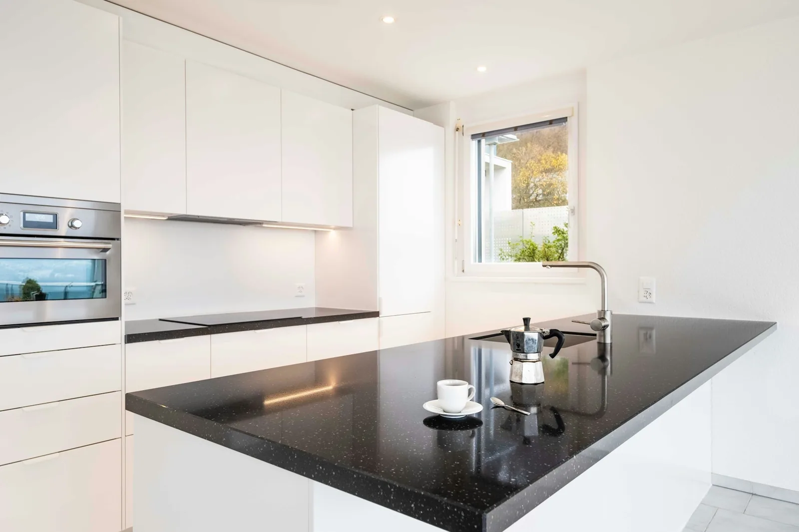 Cuisine rénovée avec meubles blancs et plan de travail sombre à Zürich.