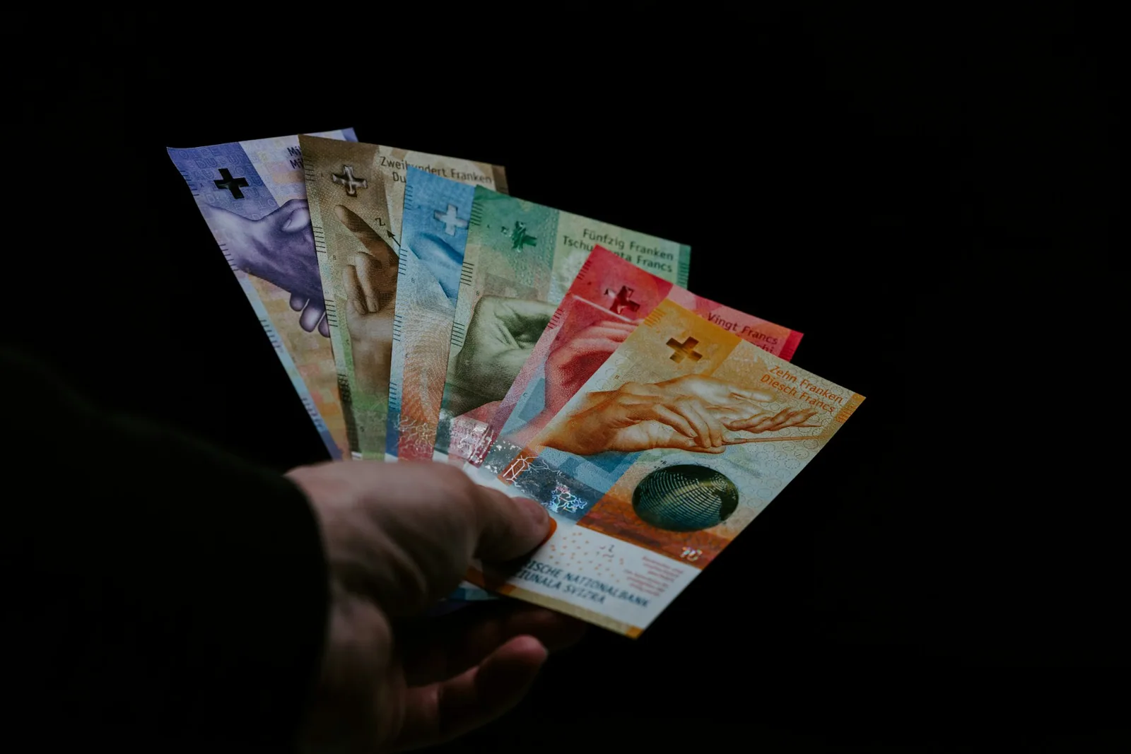 Main tenant plusieurs billets de francs suisses.