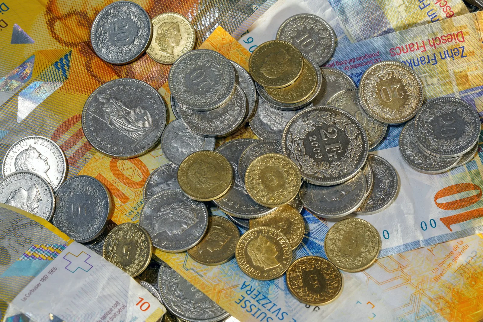 Pièces de monnaie déposées sur des billets de francs suisses.