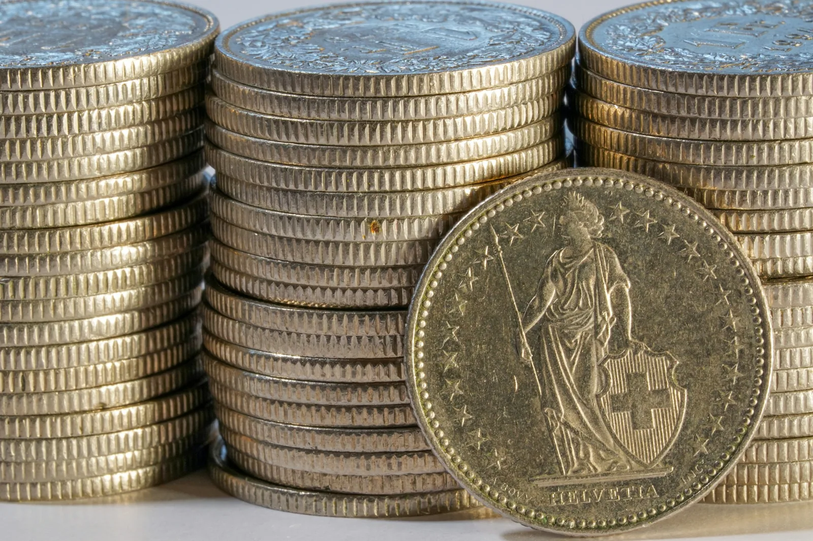 Piles de pièces suisses et pièce portant Helvetia.