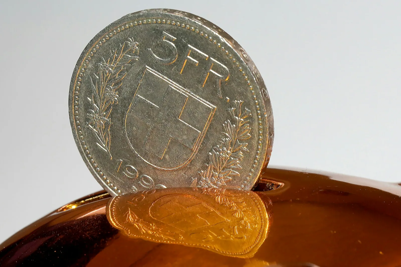 Pièce de cinq francs suisses glissée dans une tirelire.