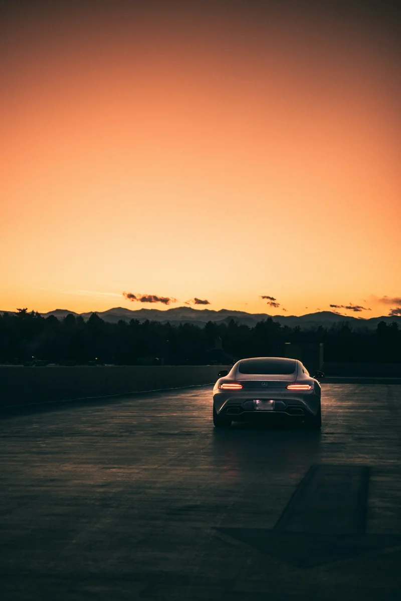 Voiture blanche sur une route au coucher du soleil.