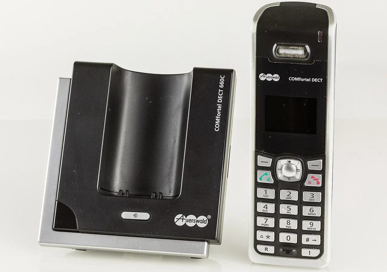 Combiné téléphonique DECT Auerswald à côté de sa base.