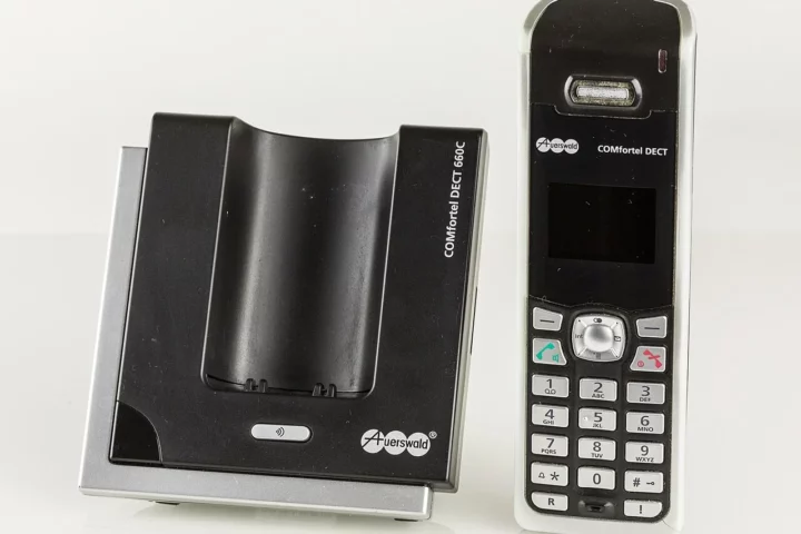 Combiné téléphonique DECT Auerswald à côté de sa base.
