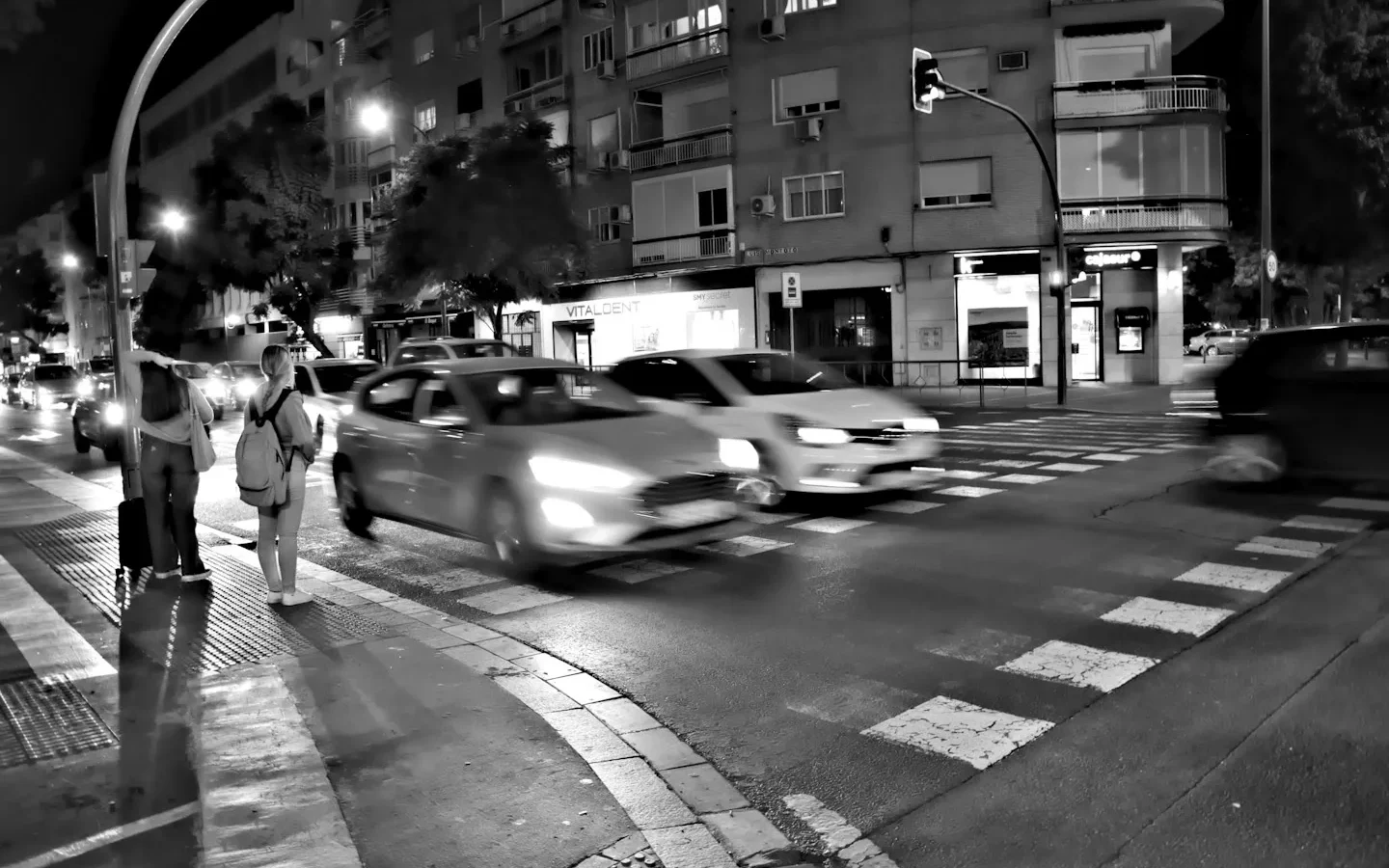 Voitures à un carrefour photographié en noir et blanc.