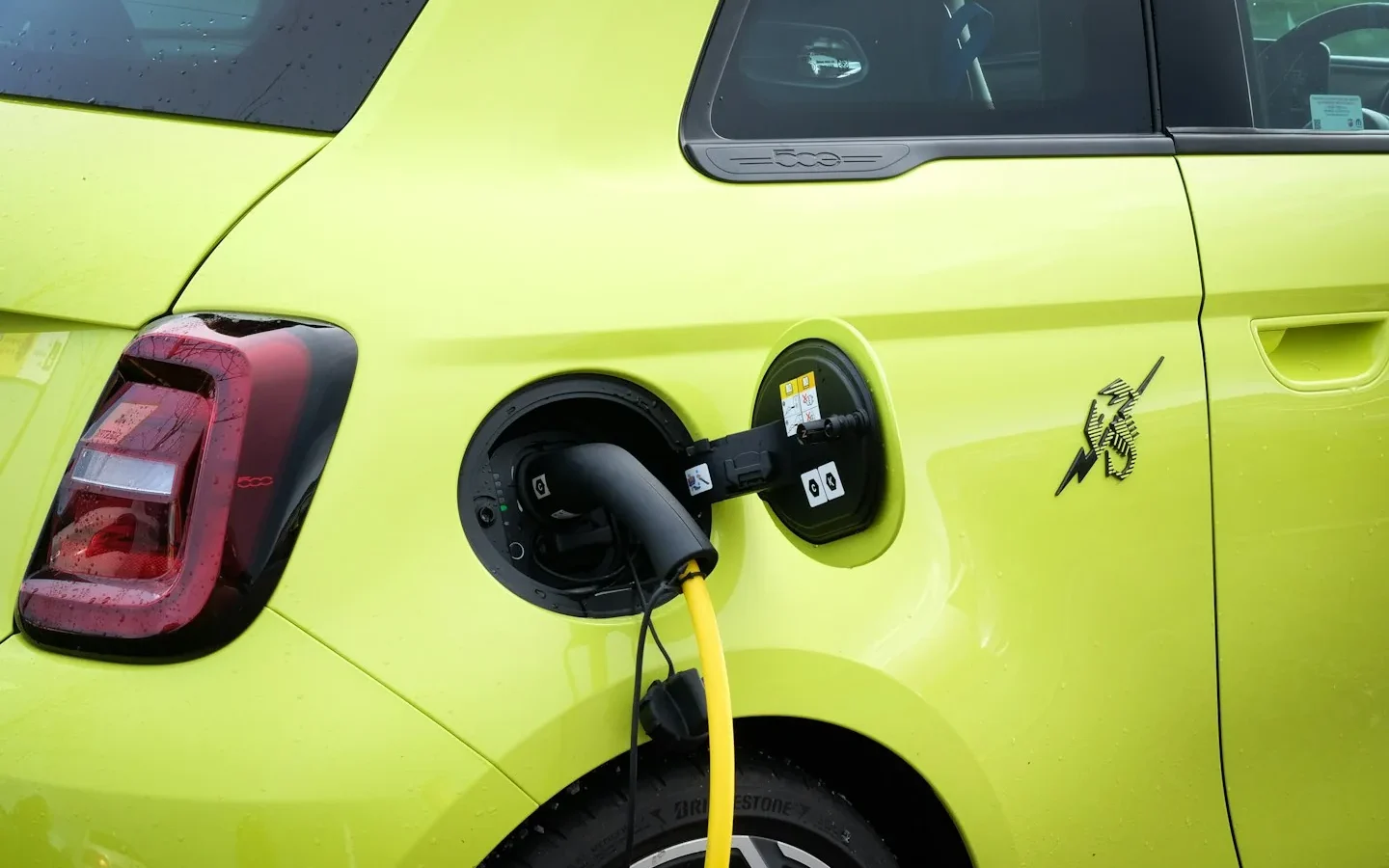 Câble de recharge branché à une petite voiture électrique jaune.