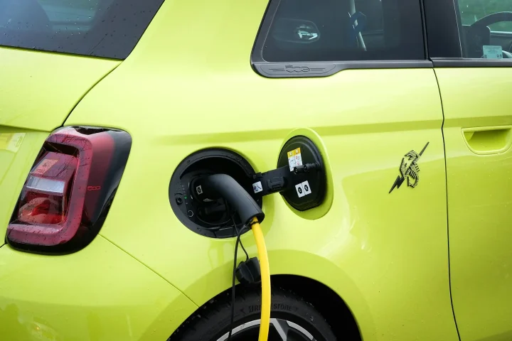 Câble de recharge branché à une petite voiture électrique jaune.