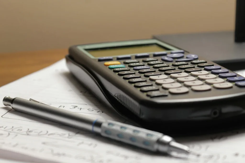 Calculatrice et stylo posés sur des documents.