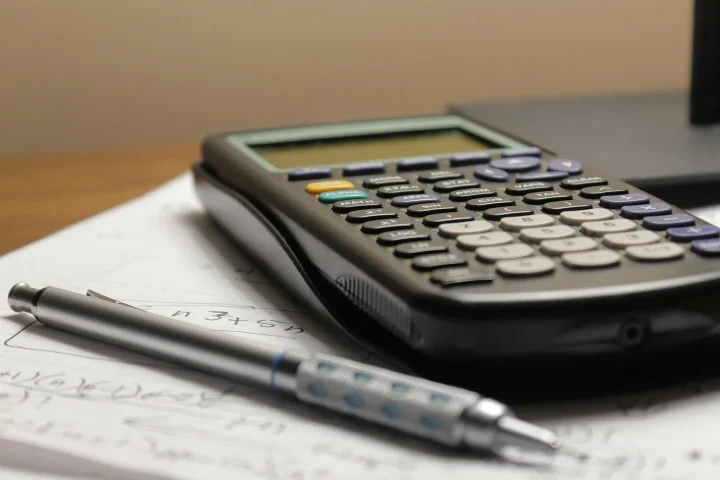 Calculatrice et stylo posés sur des documents.