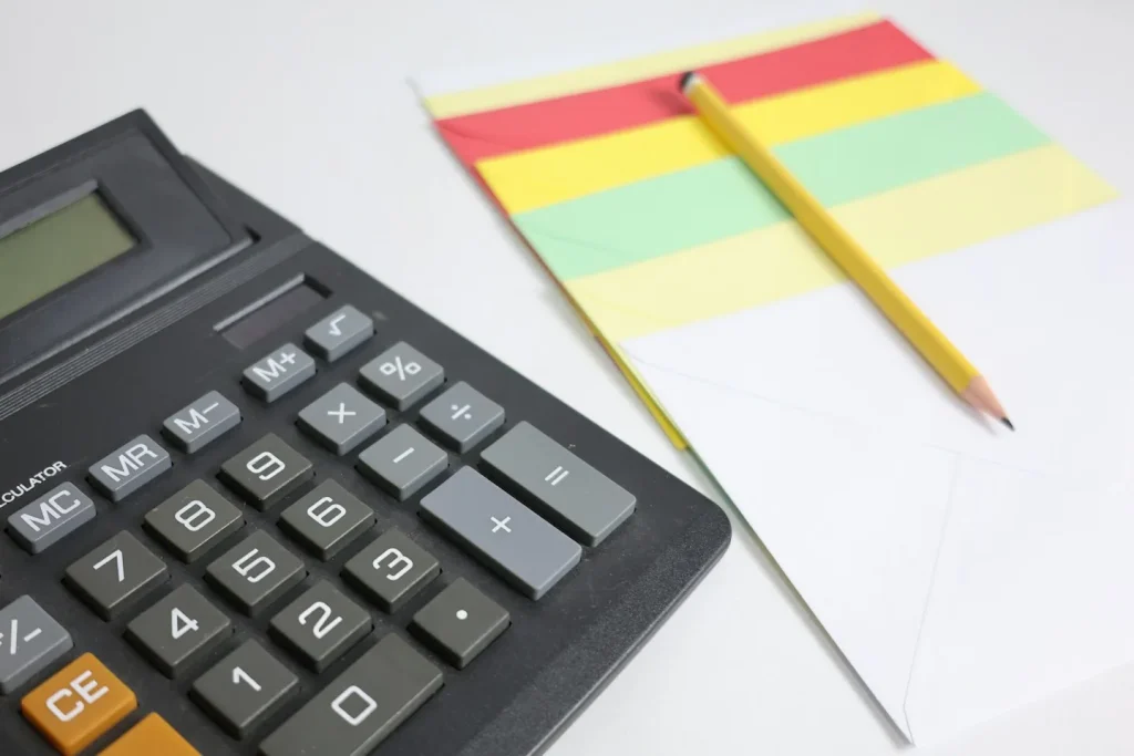 Calculatrice, crayon et bloc de notes sur une surface blanche.