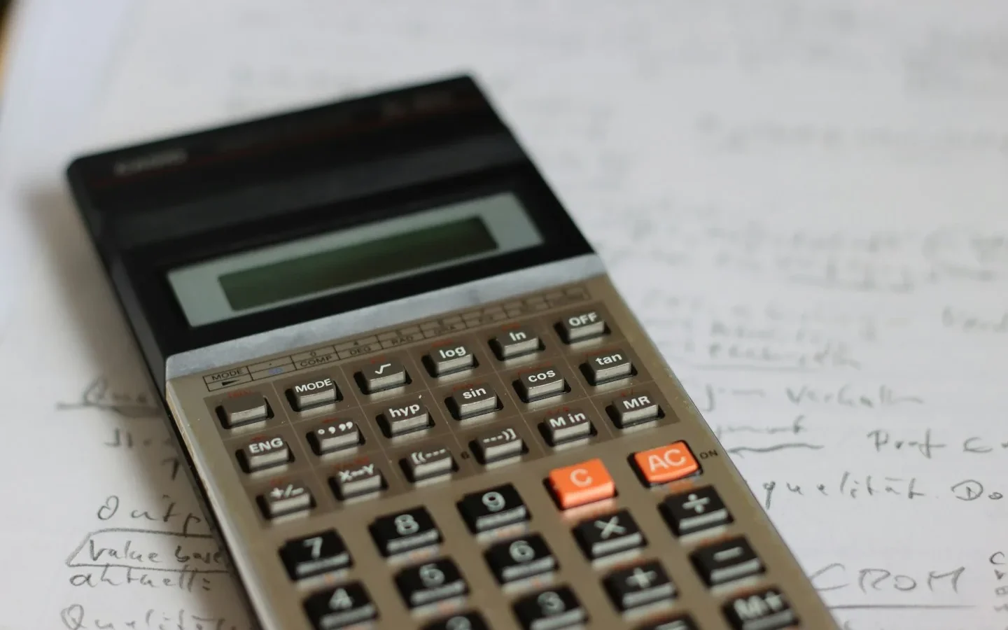 Calculatrice posée sur une feuille avec des notes.