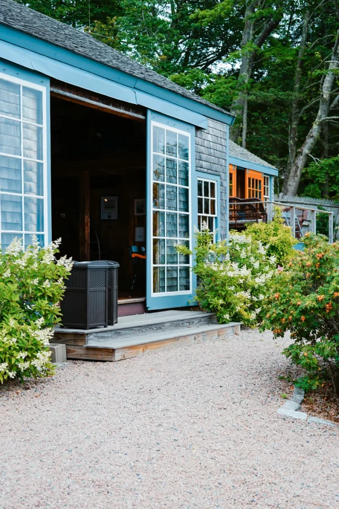Portes vitrées ouvertes sur une terrasse entourée de plantes.