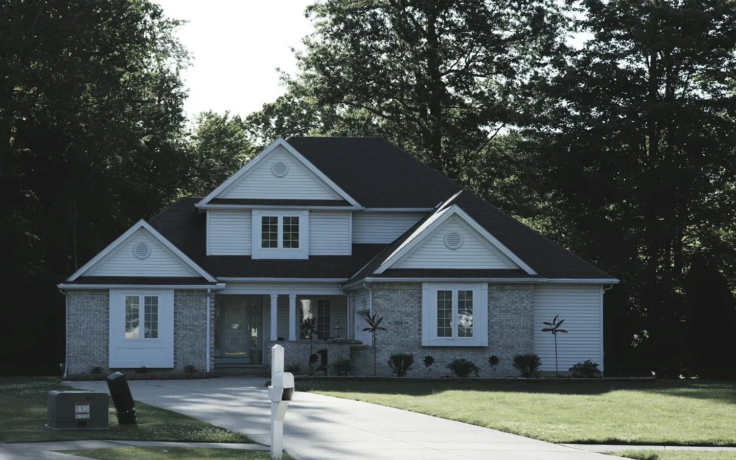 Façade d’une maison avec pelouse et arbres.