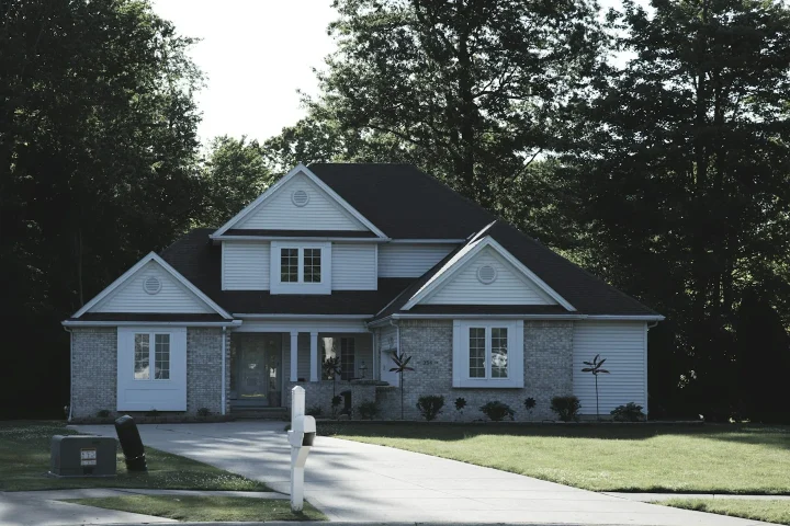 Façade d’une maison avec pelouse et arbres.
