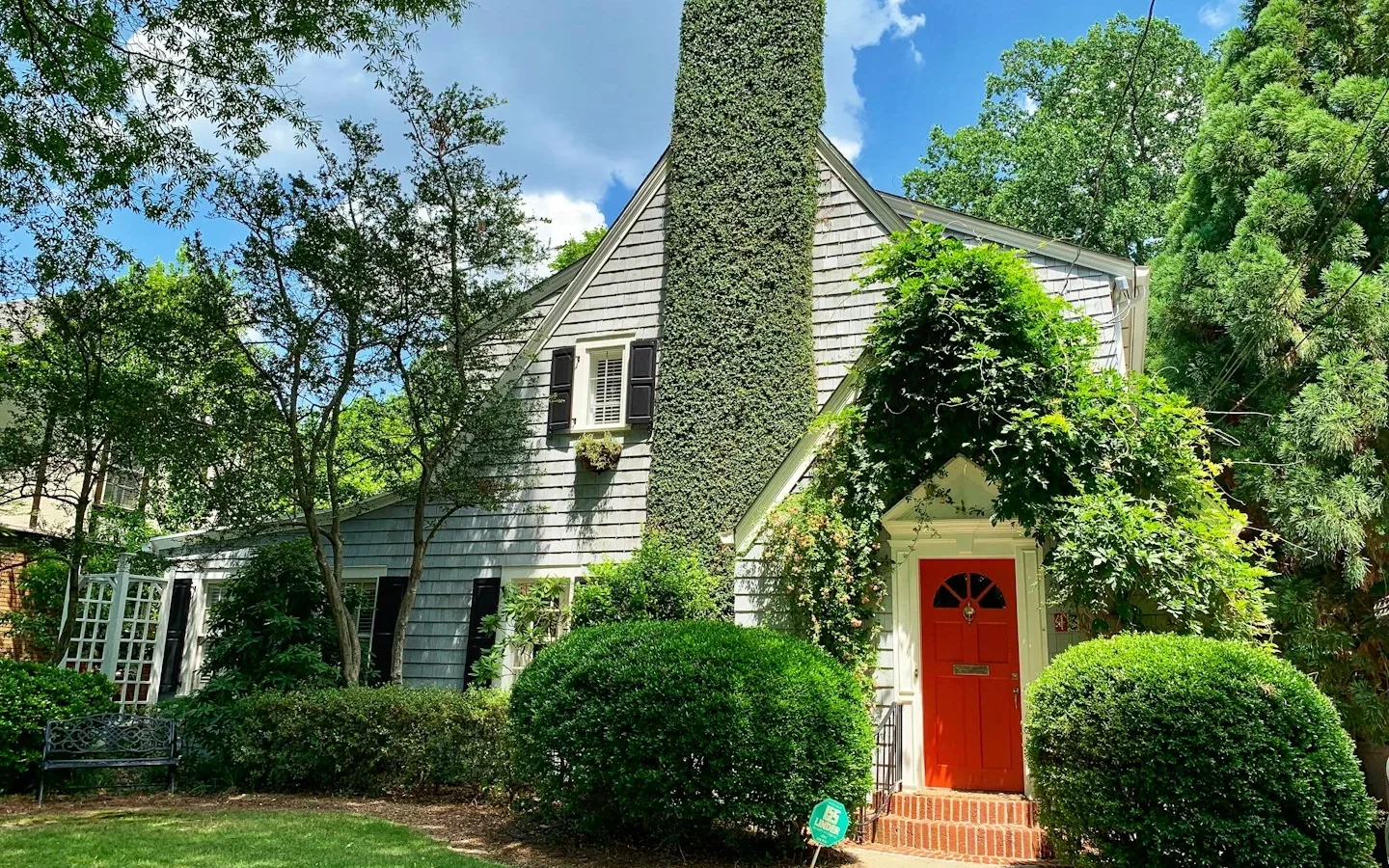 Maison entourée d’arbres avec une porte rouge.