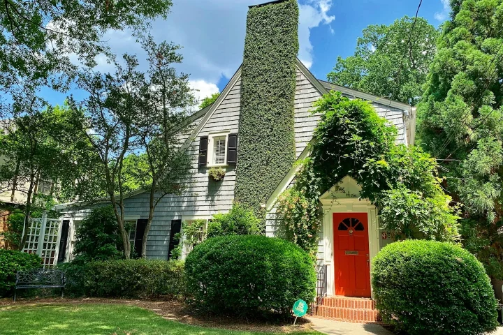 Maison entourée d’arbres avec une porte rouge.