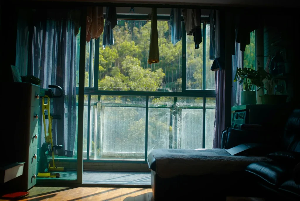 Intérieur d’un appartement avec balcon donnant sur des arbres.