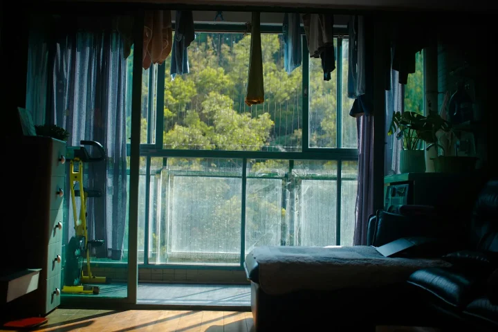 Intérieur d’un appartement avec balcon donnant sur des arbres.