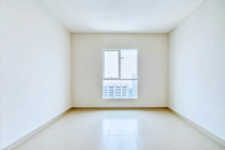 Pièce vide avec fenêtre et sol clair.