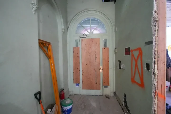 Entrée d’un bâtiment en travaux avec matériel de chantier.