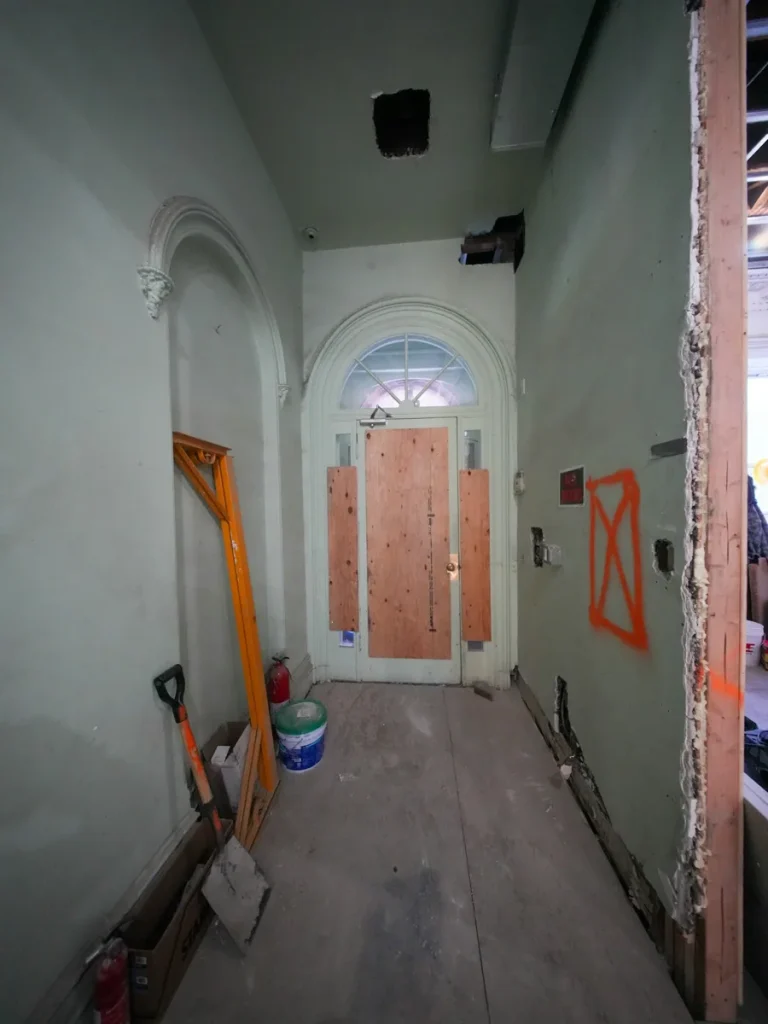 Entrée d’un bâtiment en travaux avec matériel de chantier.