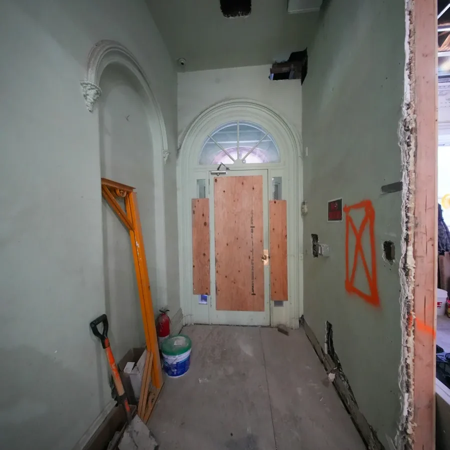 Entrée d’un bâtiment en travaux avec matériel de chantier.