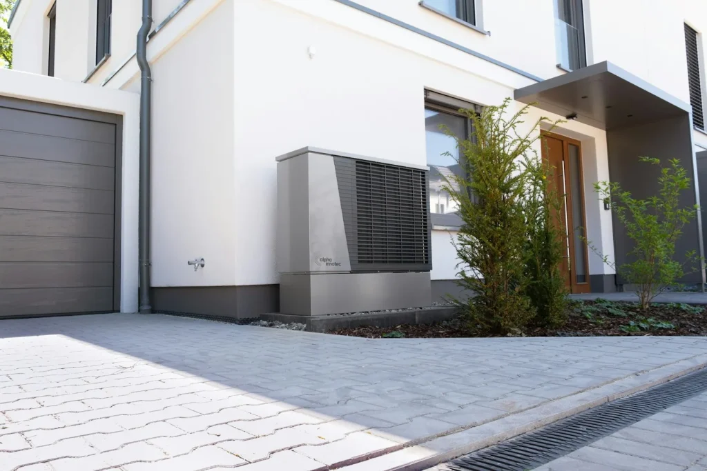 Maison avec unité extérieure de chauffage près de l’entrée.