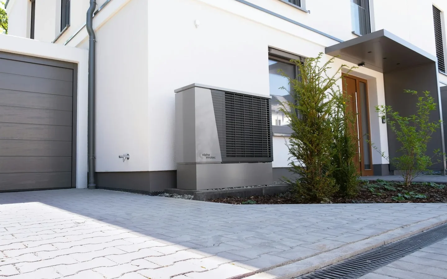 Maison avec unité extérieure de chauffage près de l’entrée.