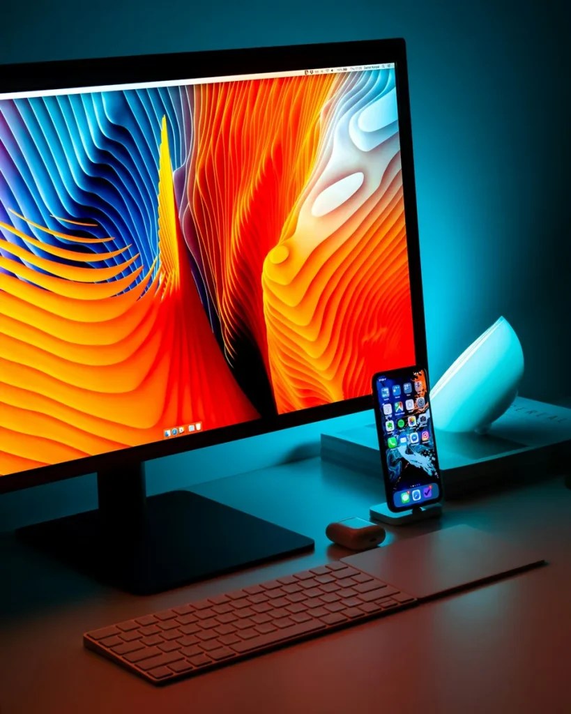 Écran de bureau et smartphone sur un poste informatique.