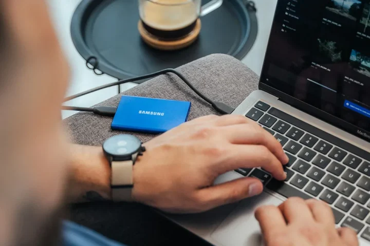 Ordinateur portable, disque externe et casque audio sur un bureau.
