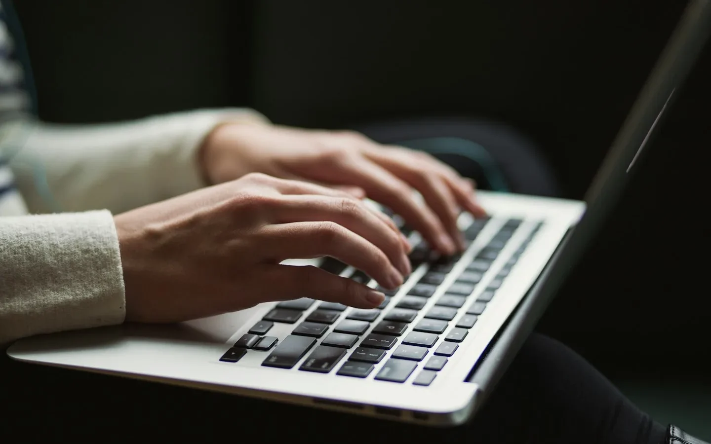 Mains saisissant du texte sur un clavier d’ordinateur portable.