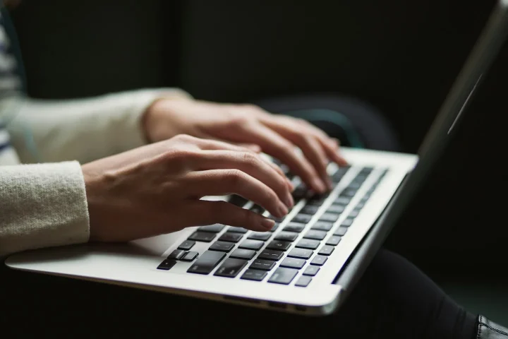 Mains saisissant du texte sur un clavier d’ordinateur portable.