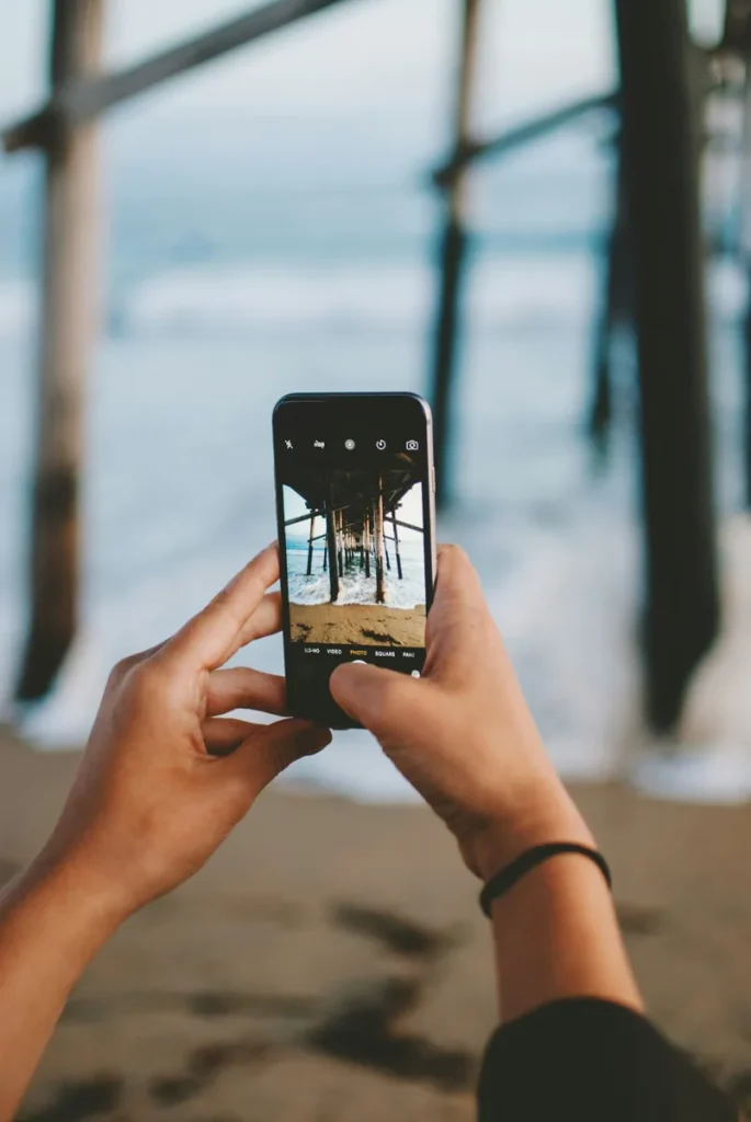 Mains tenant un smartphone pour photographier un lieu.