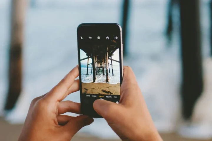 Mains tenant un smartphone pour photographier un lieu.
