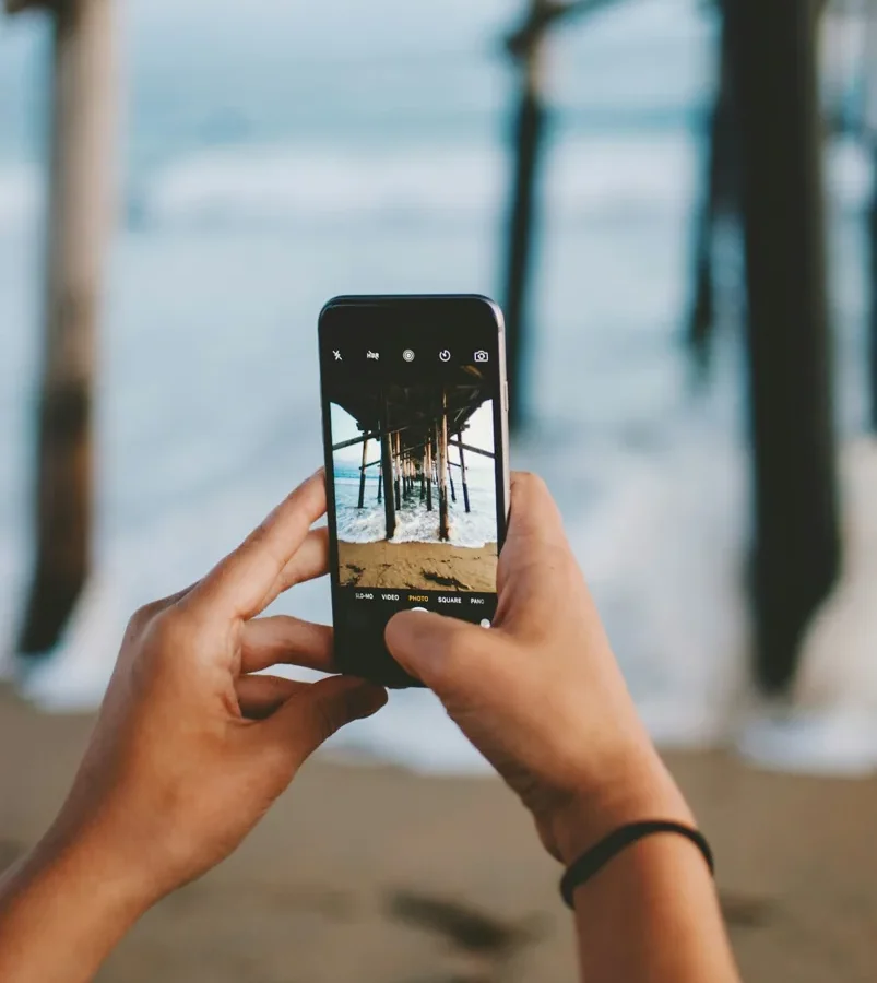Mains tenant un smartphone pour photographier un lieu.