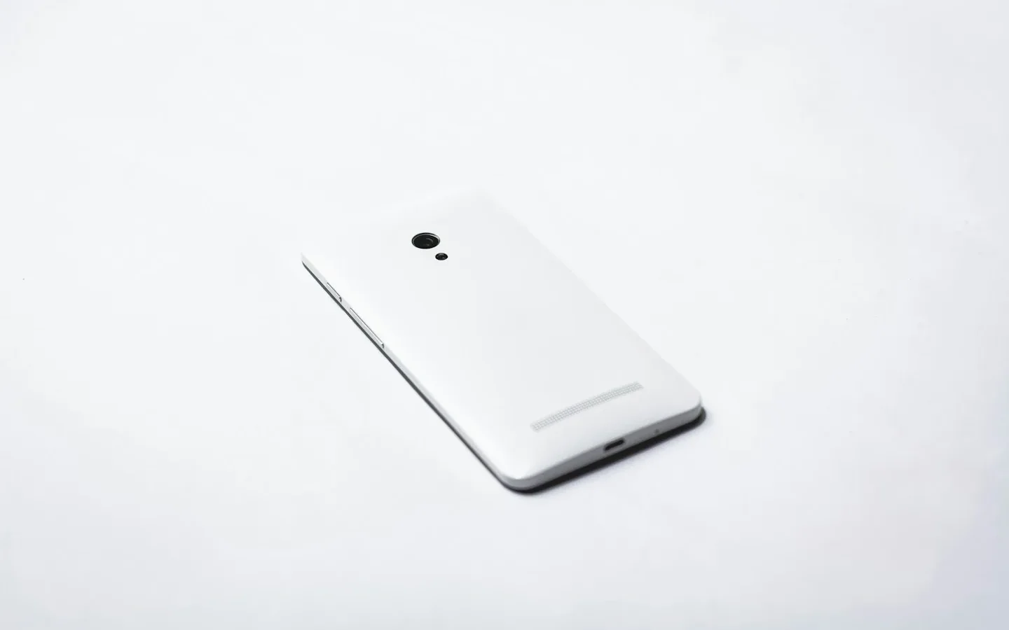 Dos d’un smartphone blanc posé sur une surface claire.