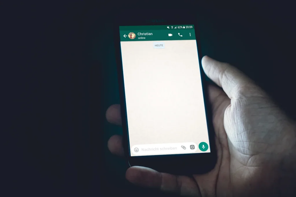Smartphone tenu en main avec une application de messagerie ouverte.
