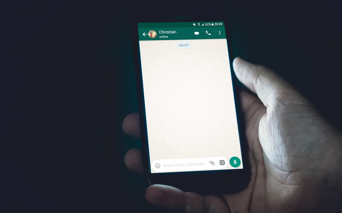 Smartphone tenu en main avec une application de messagerie ouverte.