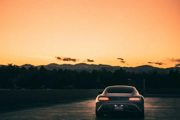 Voiture blanche sur une route au coucher du soleil.