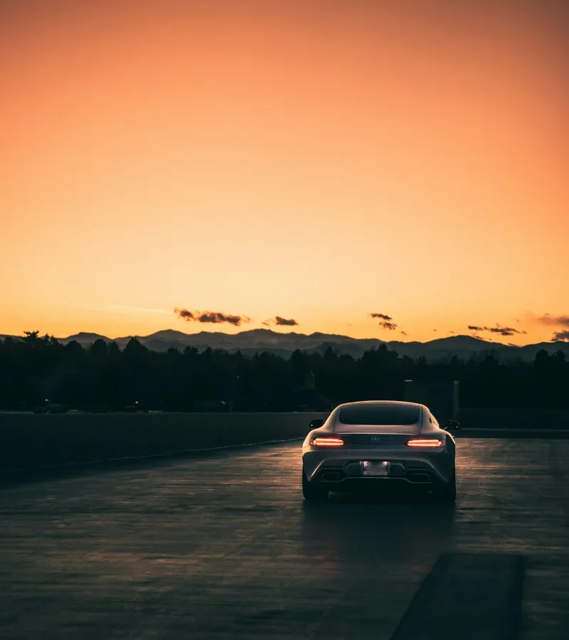 Voiture blanche sur une route au coucher du soleil.